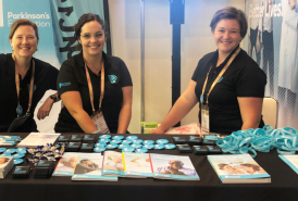 Three Parkinson's Foundation employees smiling at the Parkinson's Foundation booth at a past World Parkinson's Congress