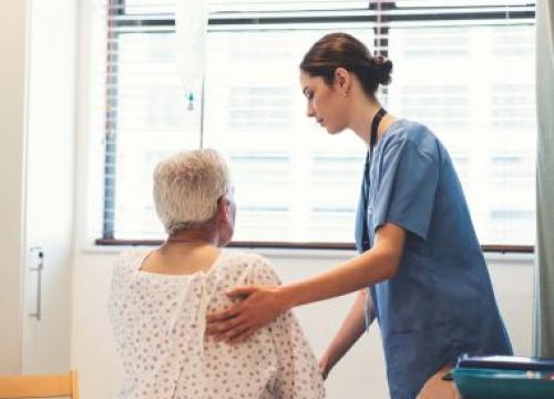 Nurse assisting patient out of hospital bed
