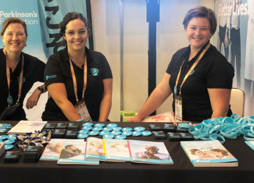 Three Parkinson's Foundation employees smiling at the Parkinson's Foundation booth at a past World Parkinson's Congress
