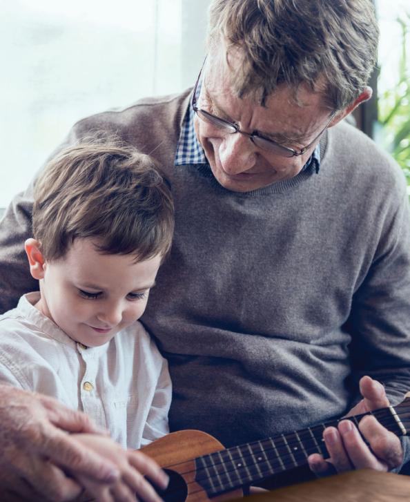 Grandfather teaching grandson how to play the guitar