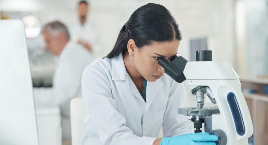 Mujer investigadora mirando un microscopio