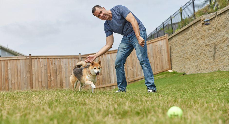 Man playing fetch with dog in the yard