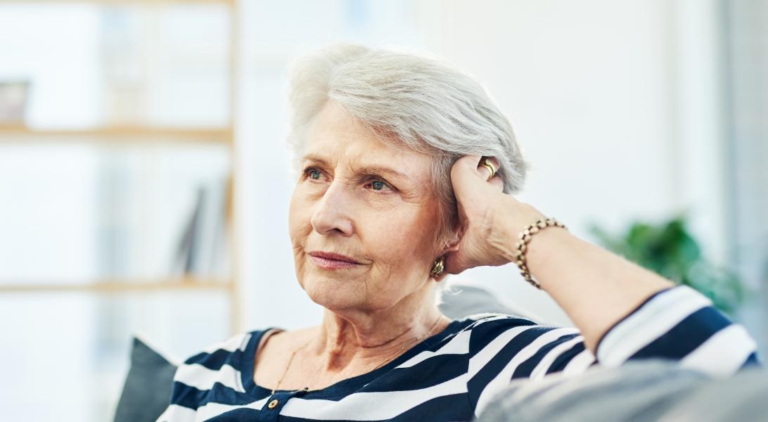 Senior woman sitting on chair- looking away- smiling stock photo