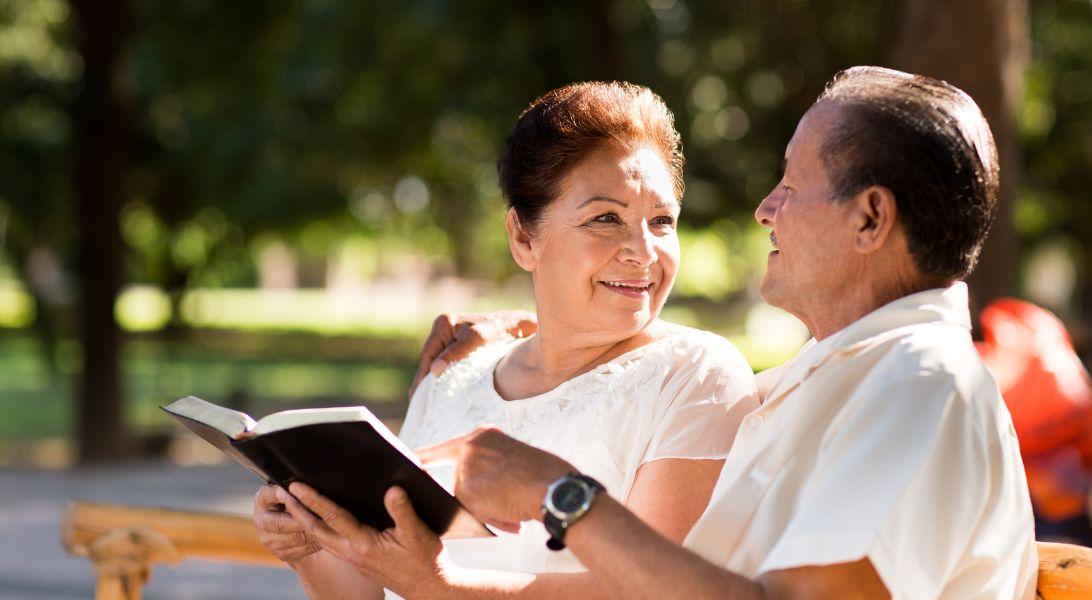 Pareja leyendo un libro afuera