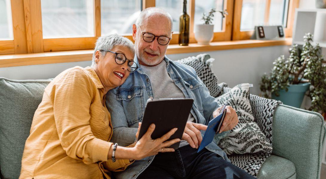 Couple sitting on couch looking at tablet