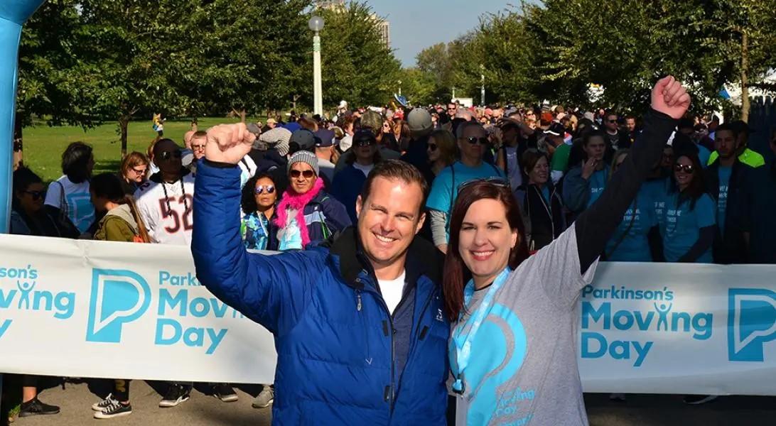 a man and a woman in PF swag standing in front of a large, excited crowd walking for PD