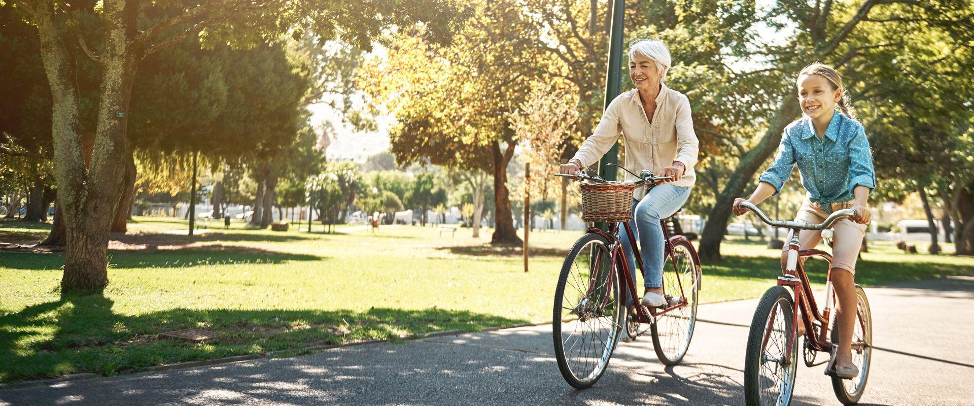 Grandma and granddaughter riding bikes in park