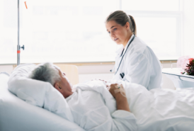 Female doctor talking to hospital patient in bed