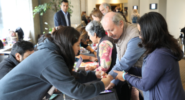 Woman putting wristband on mans hand at event table.