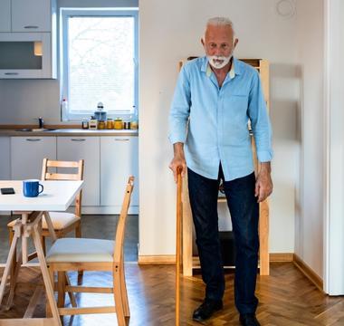 Man using cane standing still in dinning room