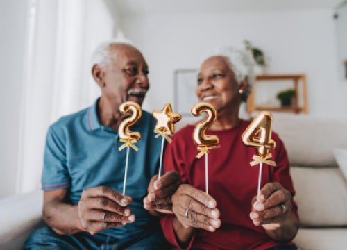 Man and woman on couch holding up 2024 sign.