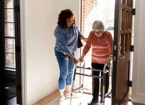 Caregiver assisting an elderly woman with a walker