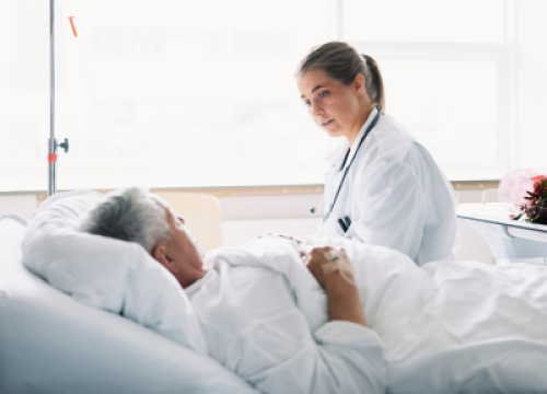 Female doctor talking to hospital patient in bed