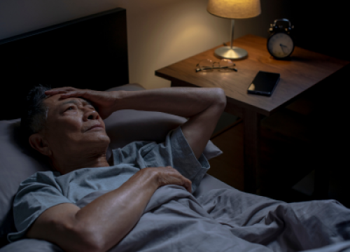 Man laying in bed having trouble sleeping