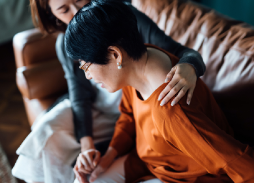 Woman helping elderly woman in pain