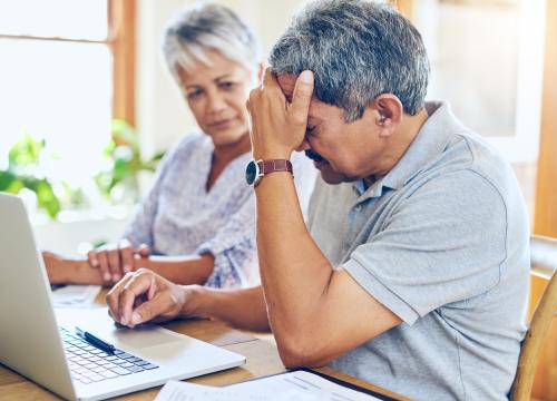 Husband frustrated while looking at laptop and wife comforting him