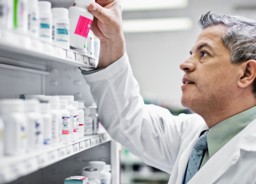 Pharmacist organizing pill bottles on a pharmacy shelf