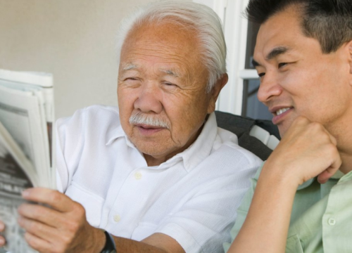 Grandfather and son reading a newspaper together