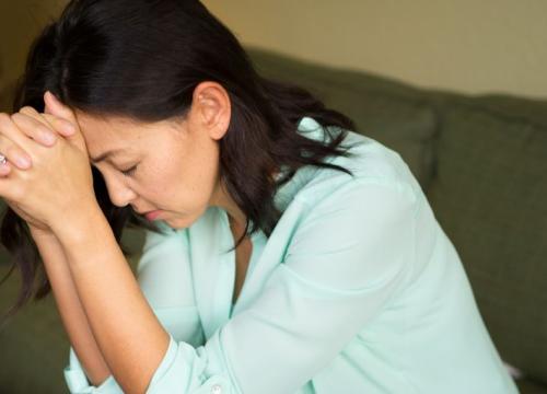 Woman with her head in her hands while experiencing dizziness