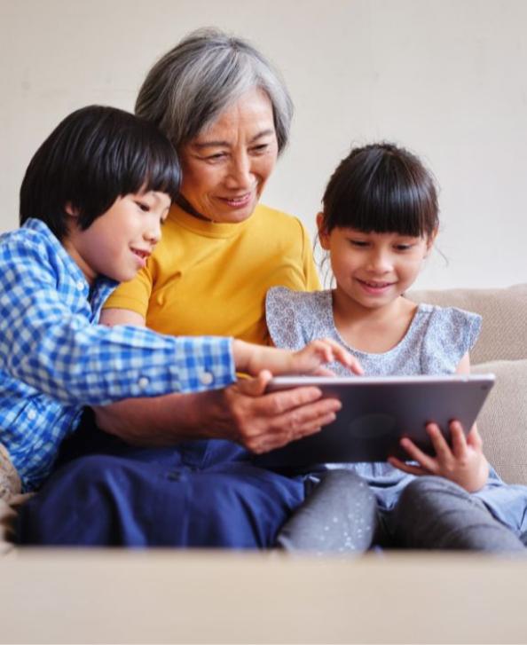 Grandma on tablet with two grandkids