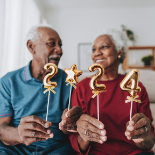 Man and woman on couch holding up 2024 sign.