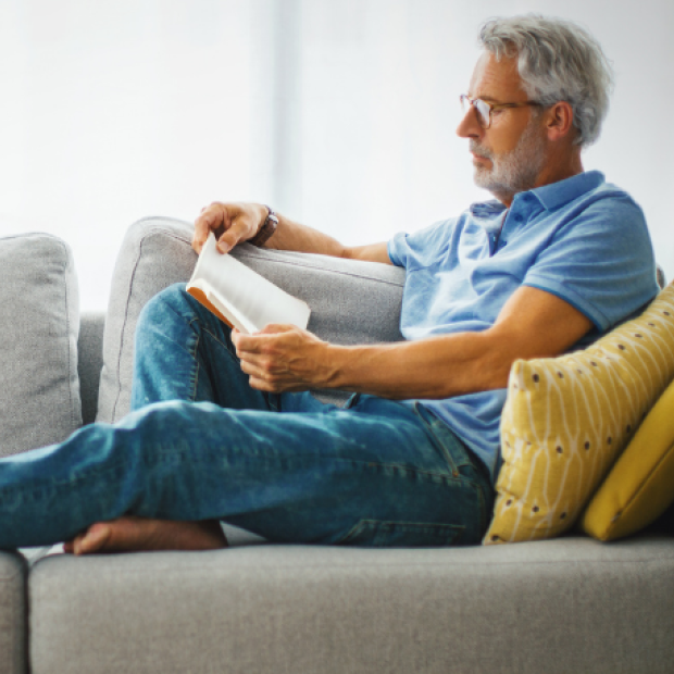 Man sitting on couch reading book