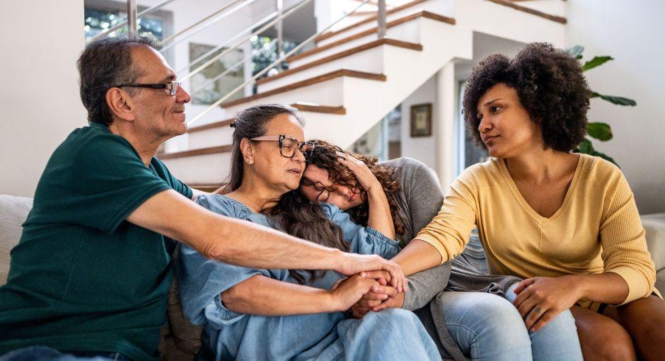 Familia consolándose mutuamente en el sofá de la sala de estar