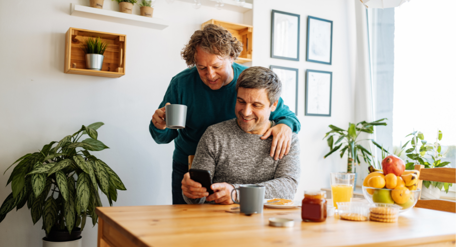 Male couple at table looking at a phone while drinking coffee