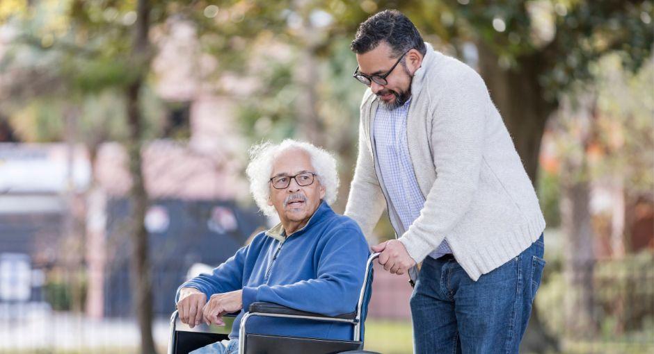 Grandson taking his grandfather for a walk in his wheelchair