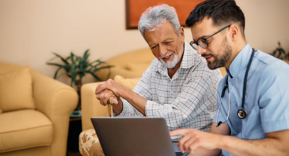 Nurse sitting with patient reviewing materials on laptop