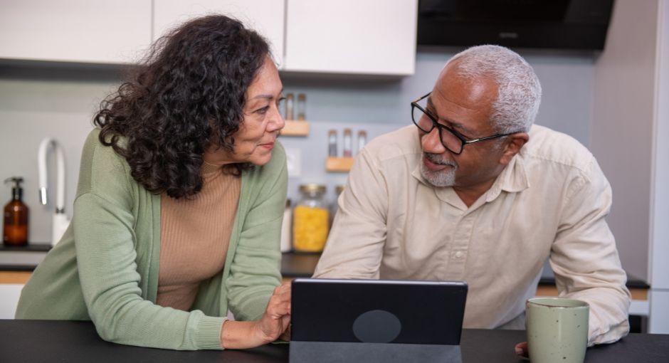 Husband and wife in kitchen on tablet