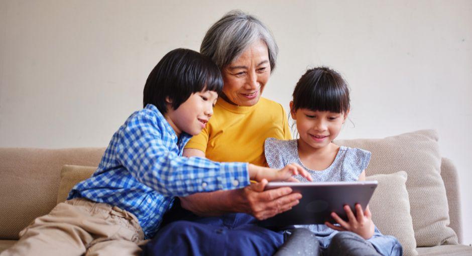 Grandma on tablet with two grandkids