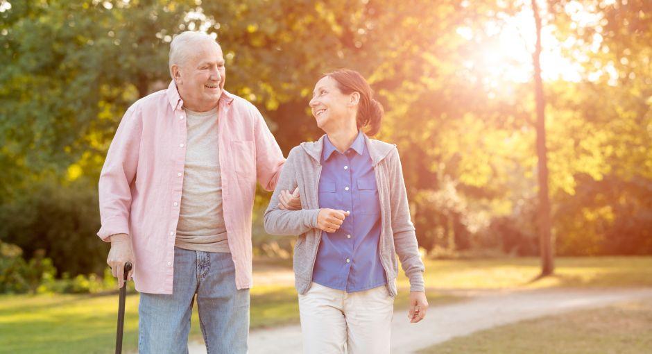 A younger woman walking with an older man, holding a cane