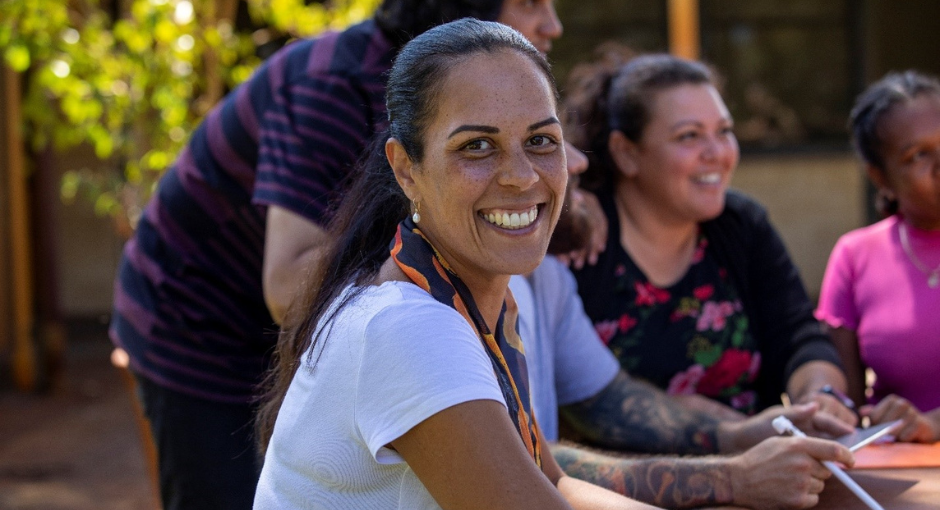 A woman sitting with a group listening to someone talking and smiling