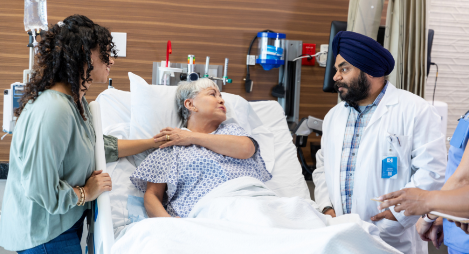 Older woman in hospital bed with two doctors at her bedside