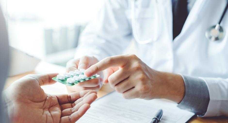 Closeup of doctor's hands pointing to pills