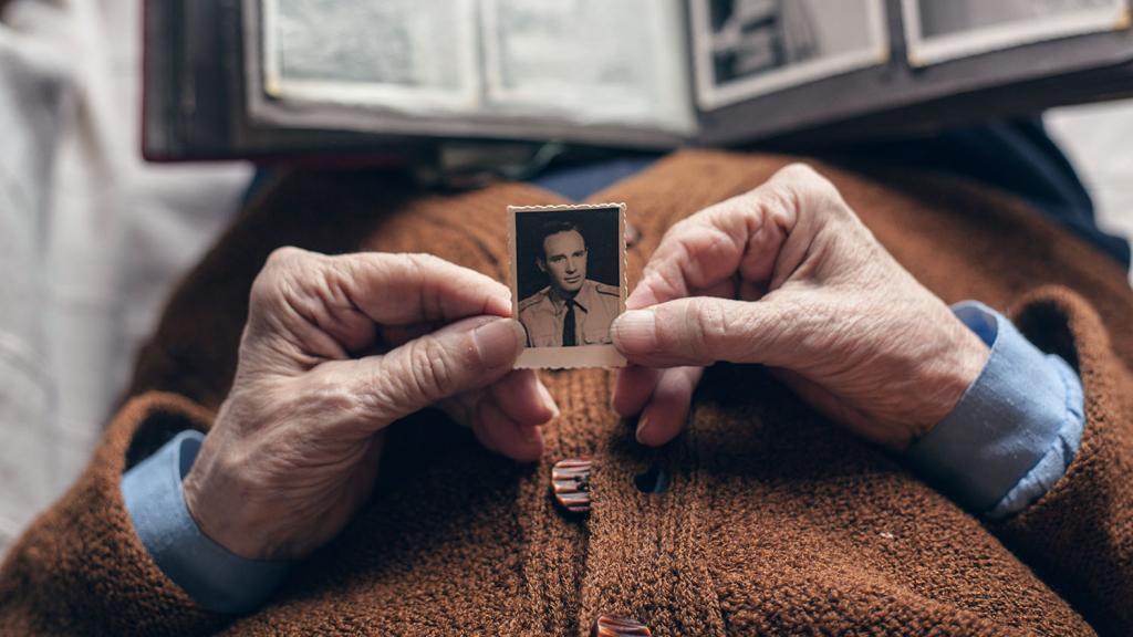 Older person holding a photograph of a young man