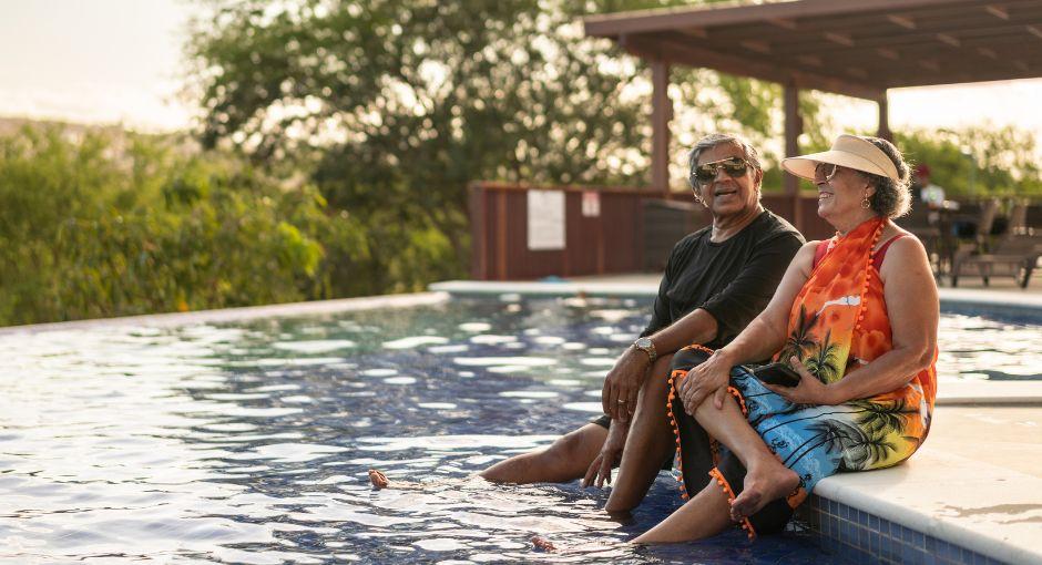 pareja sentada al borde de la piscina en un resort