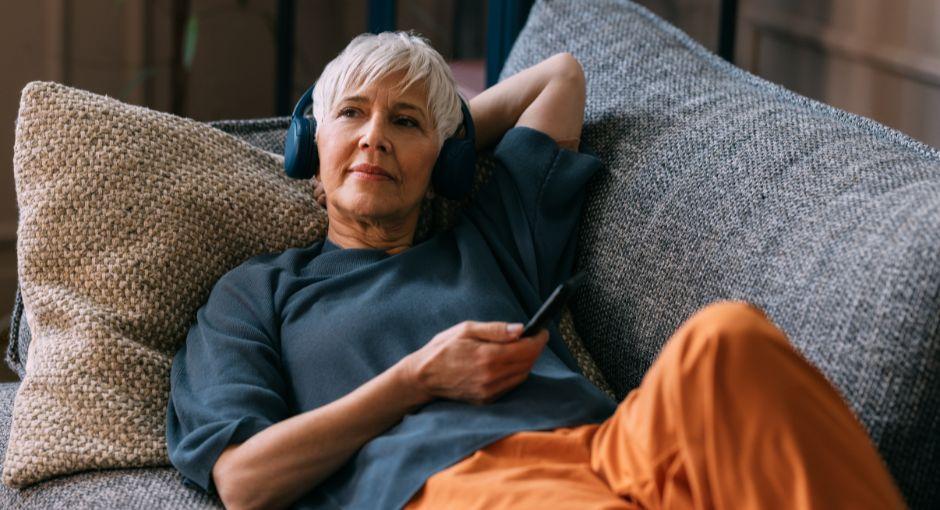 Woman laying on the couch listening to a podcast