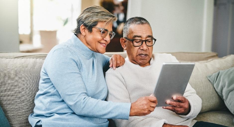 Hispanic couple on their couch looking at a tablet