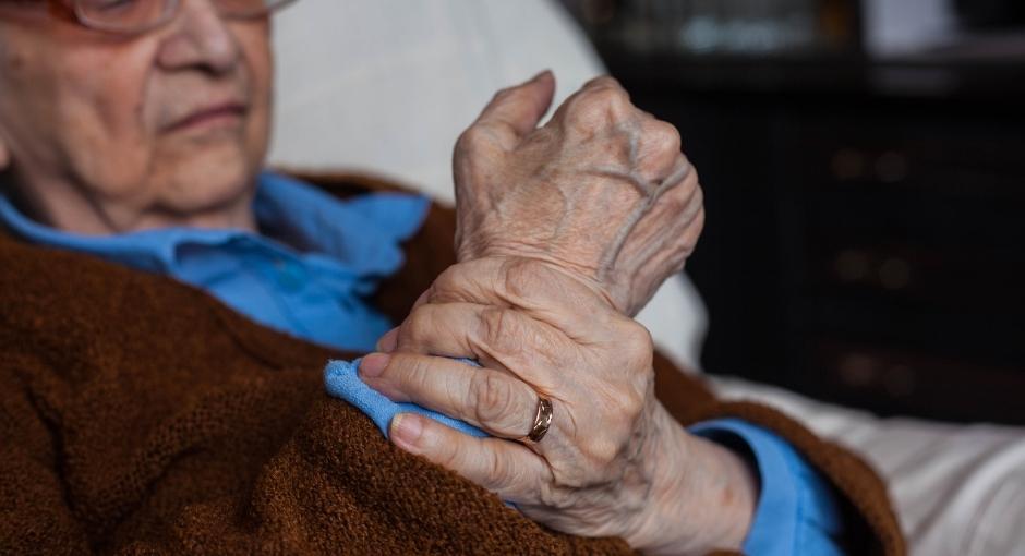 Man holding stiff wrist with opposite hand