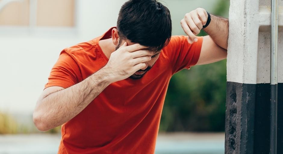 Man standing with hand on head while feeling dizzy